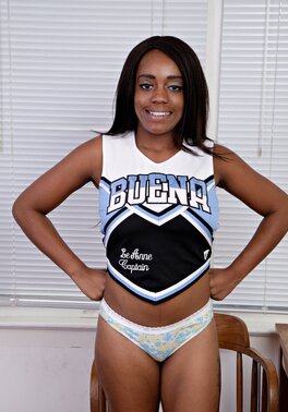 Ebony cheerleader with wonderful natural melons climbs on the table being naked