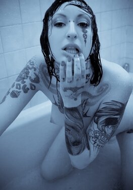 Female with a tattooed body takes a shower and brandishes her private zones