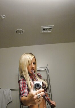 Slim young woman enjoys taking selfie in the bathroom being completely naked