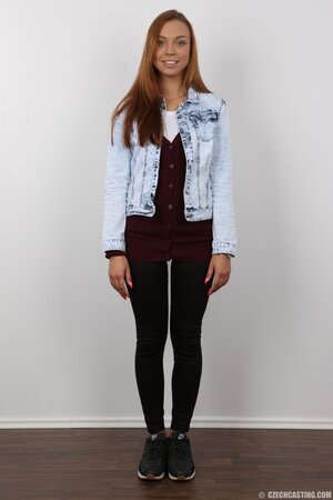 Female with red hair and bright eyes smiles and keenly strips for strangers