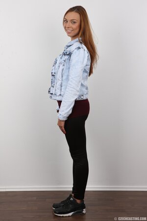 Female with red hair and bright eyes smiles and keenly strips for strangers