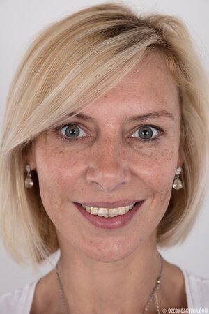 Porn model with big eyes reveals breasts and sits on stool crossing her legs