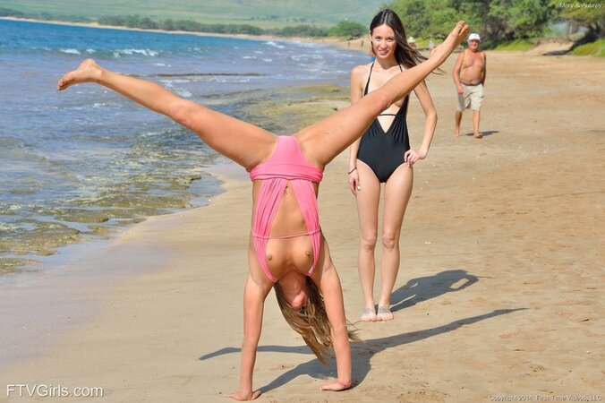 Young women rest together on the ocean shore kissing and unfolding fun parts