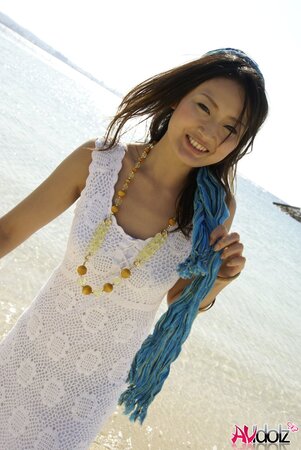 Good-looking Japanese girl in white dress walks into the water being dressed