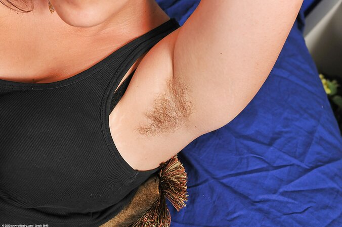 Young woman with hairy armpits and large tushy gives a footjob to man