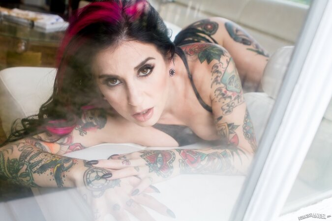 Porn queen strips in front of the glass door and continues posing on the sofa