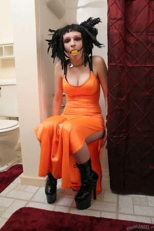 Beautiful female in orange has feathers in her hair and she spreads legs