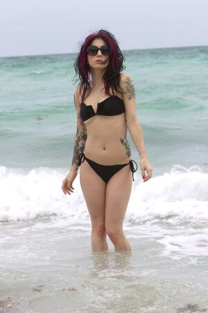 MILF with sunglasses wears black bikini and takes poses in the ocean