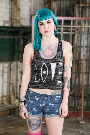 Babe with blue hair in striped stockings has a tattooed body to expose on a bench