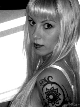 Blonde woman with tattooed body poses naked in the black and white