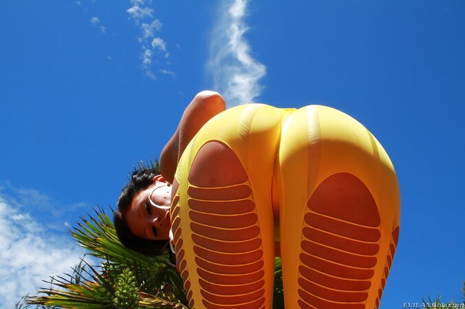 Black-haired lady demonstrates outdoors her perfect butt wrapped in yellow outfit