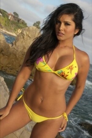 Ravishing brunette goes on rocky beach to pose under sun in yellow bikini