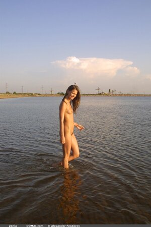 Svelte cutie with small tits and long legs poses absolutely naked on empty beach