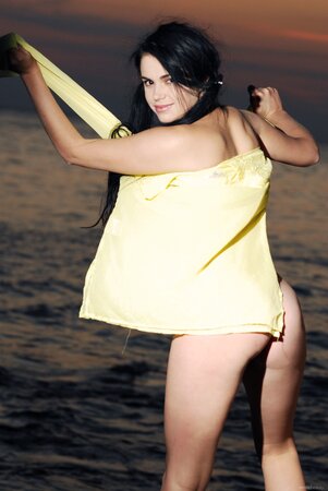 Chick with cool black hair in yellow cape feels better without it on the rocks