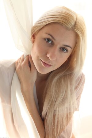 Young naked blonde looks like an angel and poses like a lustful sex demon