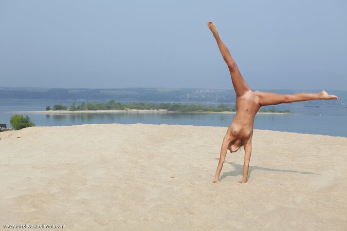 Tanned blonde demonstrates her flexible body posing in the nude on the beach