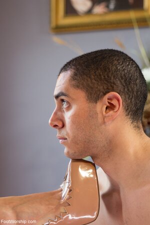 Dominatrix in a latex skirt rests her feet on his face and beyond