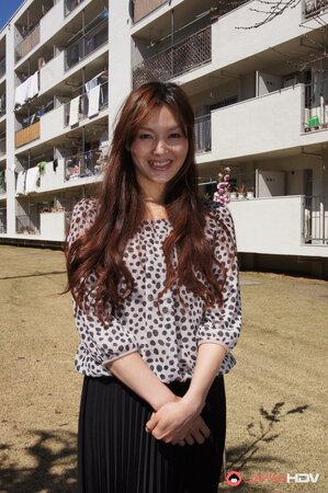 Eastern redhead in a shirt poses for photographer against a apartment building