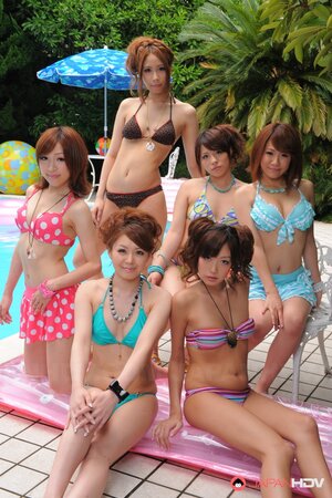 Oriental girlfriends in skimpy bikinis rest half-naked with men poolside