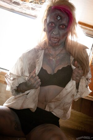 Horny zombie with big tits tears off her clothes in fetish pics