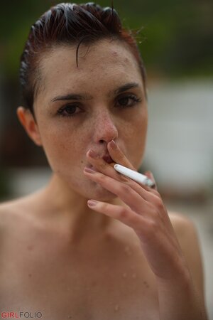 Short red-haired girl with freckles smokes after getting wet