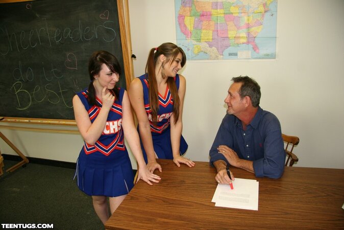Two cheerleaders jerk off their geography teacher right on top of his desk